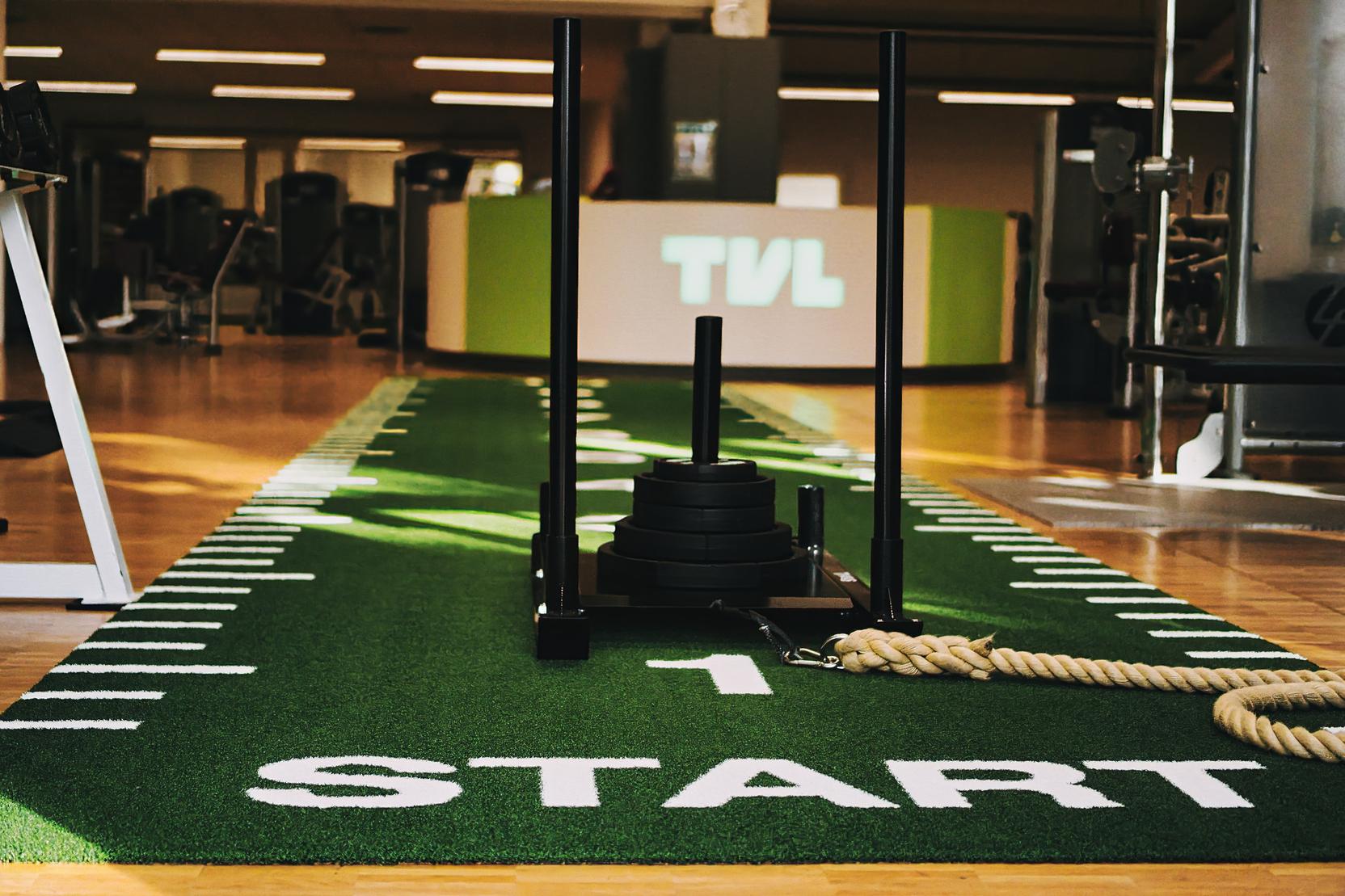 Nahaufnahme einer Fitnesszone mit einem Schlitten, der auf einem gr&uuml;nen Sportboden mit dem Wort "START" liegt.